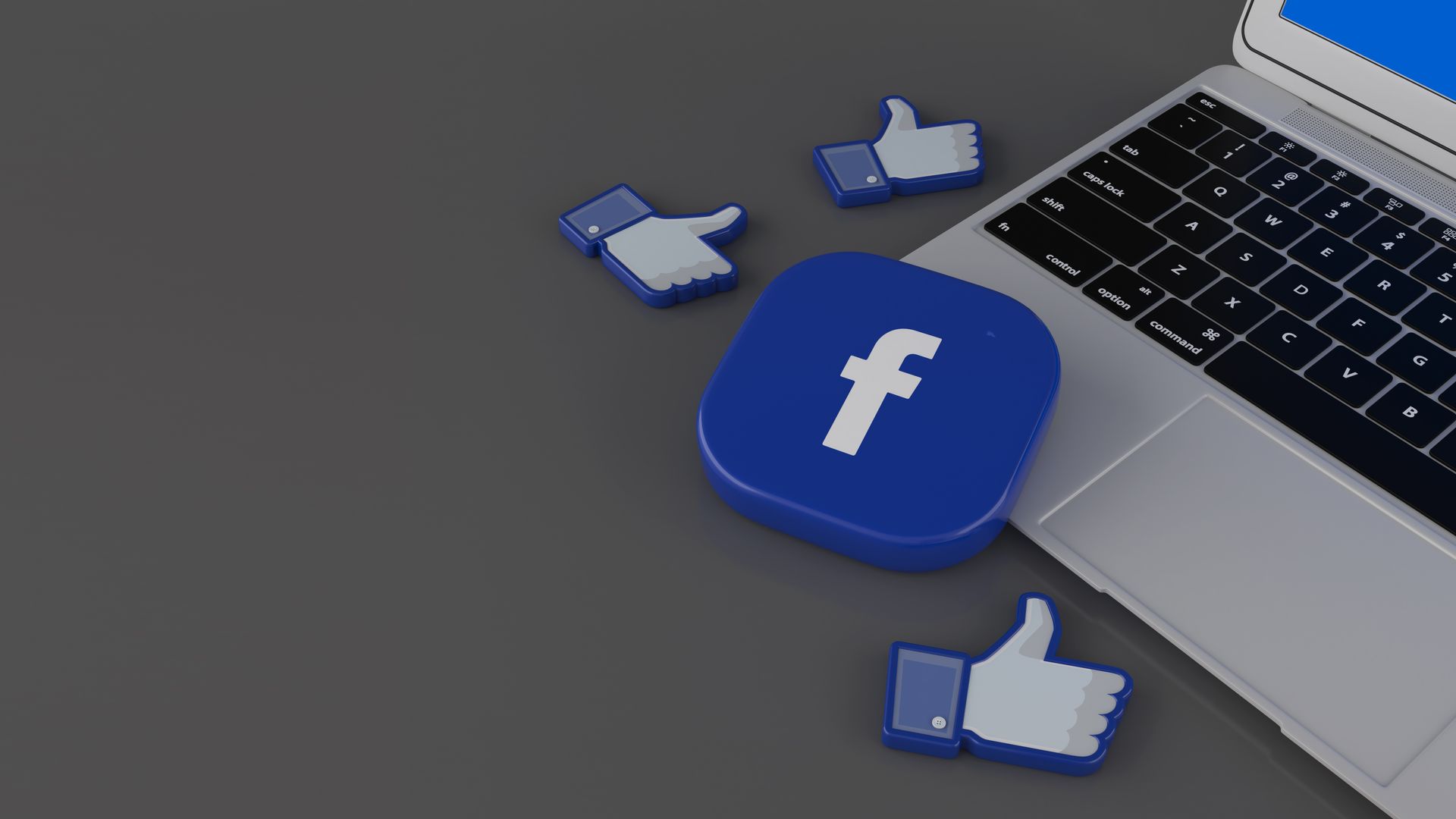 renderizacao em 3d de alguns icones de curtir e um emblema quadrado do facebook sobre o laptop em fundo cinza.jpg